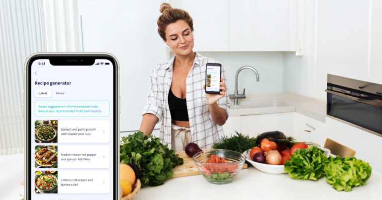 Woman surrounded by fresh product in the kitchen holds up mobile phone with Recipe Generator